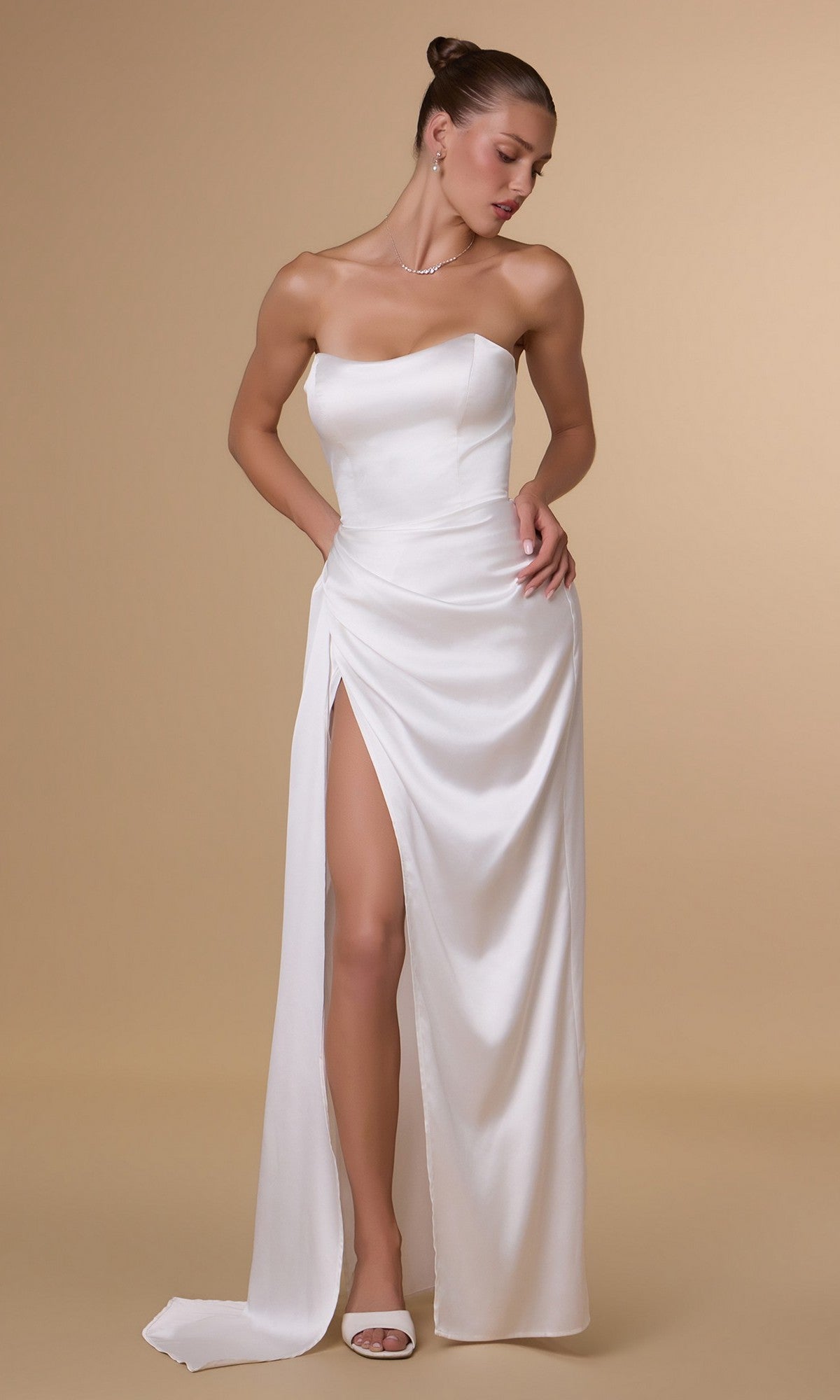 Woman in an off white Strapless Long Satin Prom Dress: Amoris T215W with a high slit stands on a beige background, looking down.